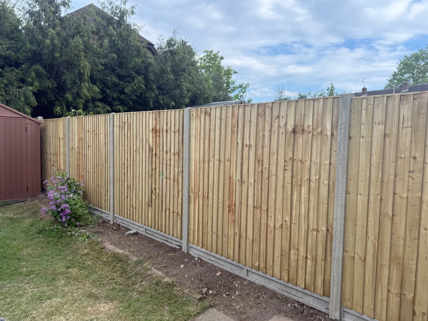 Long run of closeboard fence panels and gravel boards in a garden