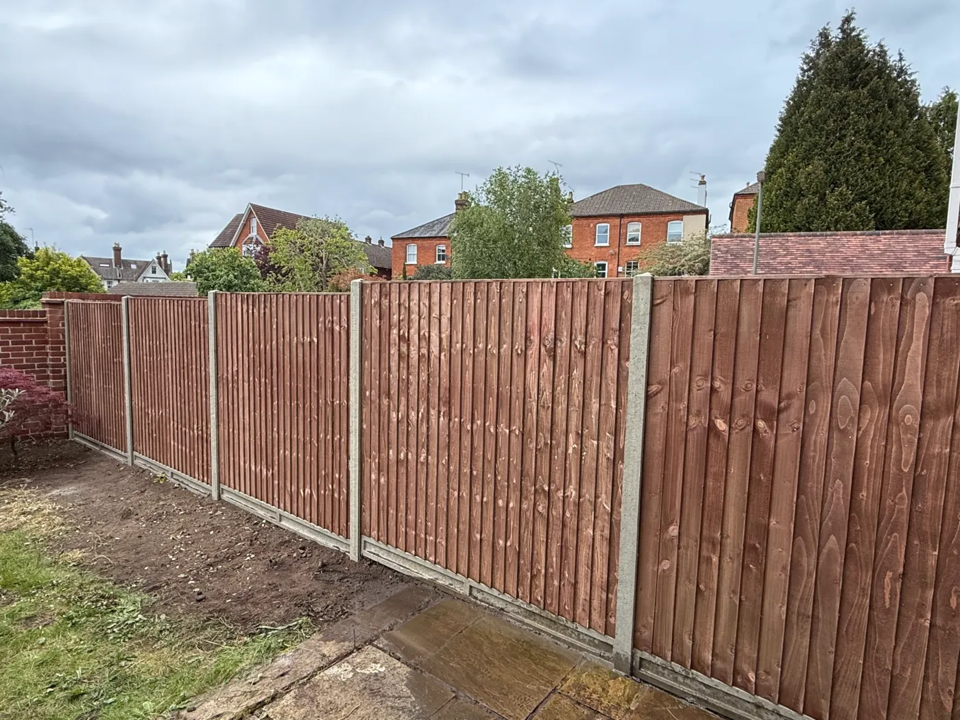 Brown stained closeboard fencing with concrete posts behind a Hampshire house