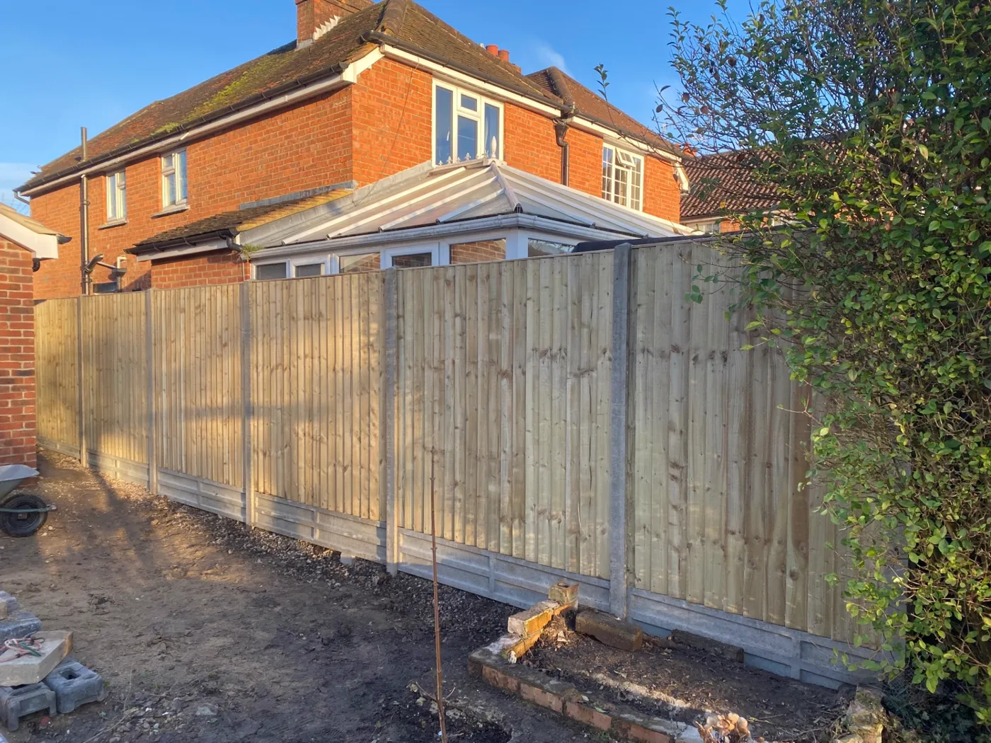 New closeboard fence installation with concrete posts and gravel boards home